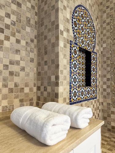 a bathroom with a tile wall with a window and towels at La Alcazaba de Triana in Seville