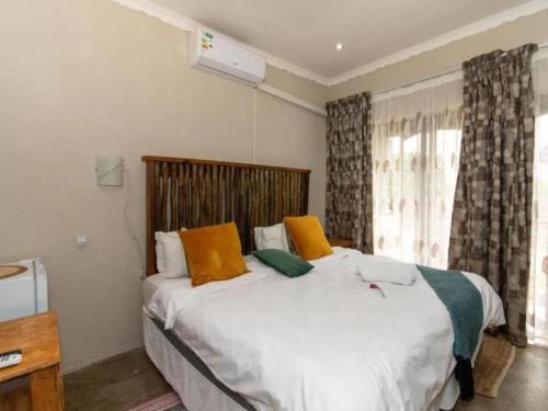 a bedroom with a bed with orange and green pillows at Woodpecker's Guest House in Hazyview