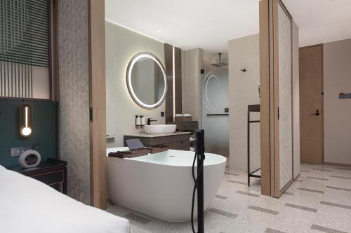 a bathroom with a tub and a sink and a mirror at Dangkou Ancient Town Hotel Wuxi MGallery Collection in Wuxi