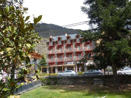 a large red building with cars parked in front of it at Hotel Vall d´Aneu in Esterri d'Àneu