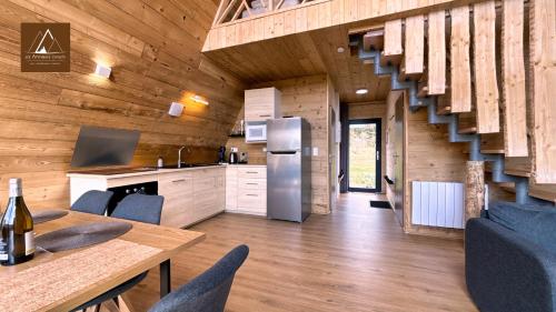a kitchen and dining room of a log cabin with a staircase at Les Atypiques Chalets in Barbey-Séroux