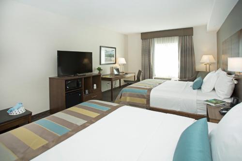 a hotel room with two beds and a flat screen tv at Wingate by Wyndham Calgary Airport in Calgary