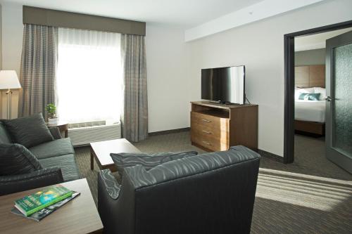 a living room with a couch and a tv in a hotel room at Wingate by Wyndham Calgary Airport in Calgary