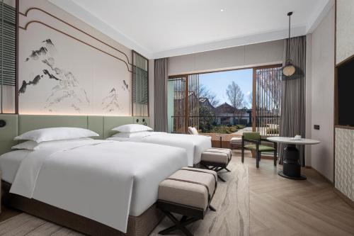 a bedroom with three beds and a large window at Dangkou Ancient Town Hotel Wuxi MGallery Collection in Wuxi