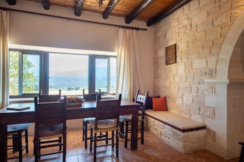 comedor con mesa, sillas y pared de piedra en Anemole Traditional Cretan Villa, en Megála Khoráfia