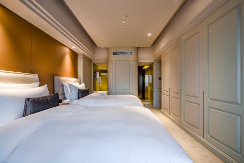 a hotel room with two beds and a hallway at Elegant International Hotel Shanghai - Bund Sichuan Road North Metro Station Branch in Shanghai