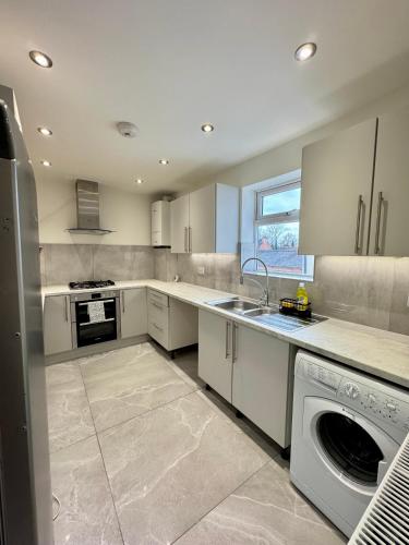 a large kitchen with white cabinets and a dishwasher at Double Bedroom in Birmingham Near City Center in Birmingham