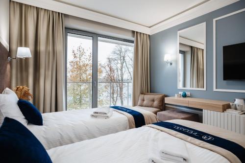 a hotel room with two beds and a large window at Hotel Pulaski Residence in Ełk