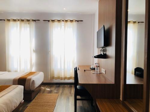 a hotel room with a bed and a desk with a television at Manigram Bishram Batika Pvt Ltd in Bhairahawa