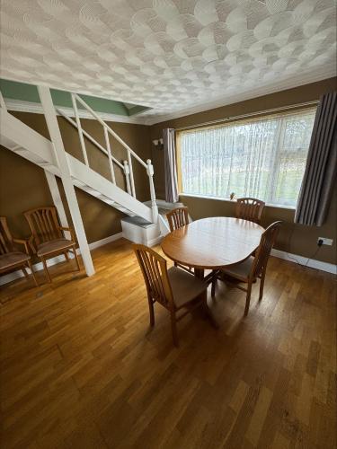 a dining room with a table and chairs and a staircase at Springfield oaks cottage in Newport