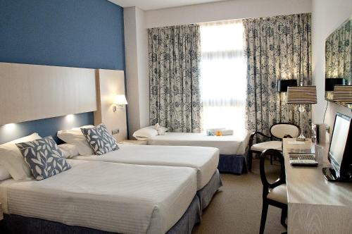 Una habitación de hotel con dos camas y un televisor. en Hotel Nuevo Boston, en Madrid