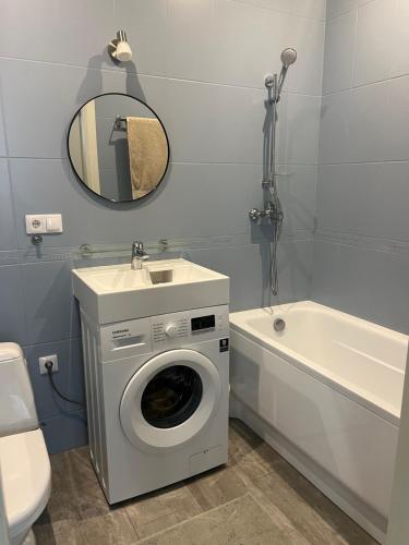 La salle de bains est pourvue d'un lave-linge, d'un lavabo et d'une baignoire. dans l'établissement Brand new apartment in a historical location, à Riga