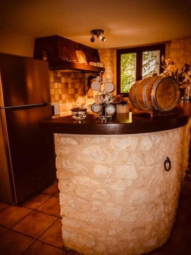 - une cuisine avec un grand comptoir en pierre et un réfrigérateur dans l'établissement Grange authentique en Quercy, à Pinsac