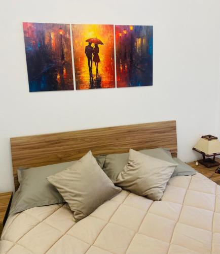a bedroom with two paintings of a couple under an umbrella at Ca di nonni in Ortovero