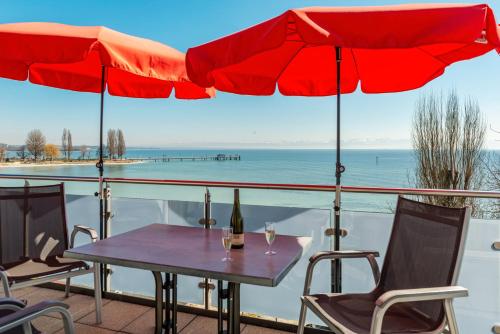 a table and chairs with red umbrellas on a balcony at Gästehaus D i c k r e i t e r in Immenstaad am Bodensee