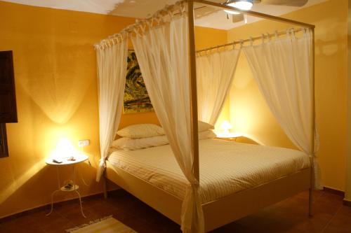 a bedroom with a canopy bed with two lamps at La Posada del Recovero in Genalguacil