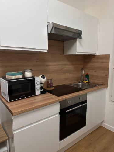 une cuisine avec un micro-ondes et un évier dans l'établissement 2-room apartment Argenteuil, à Argenteuil