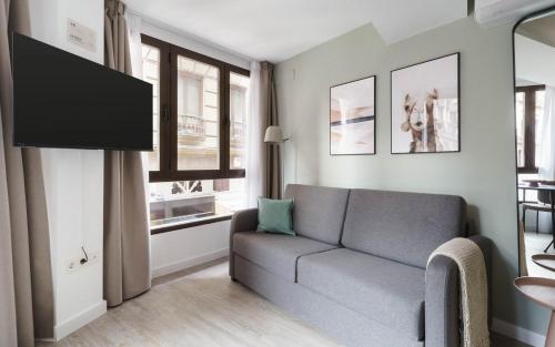 a living room with a couch and a tv at Limehome Granada Calle Lopez Rubio in Granada