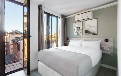 a bedroom with a bed and a large window at Limehome Granada Calle Lopez Rubio in Granada