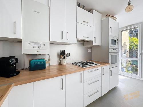 - une cuisine blanche avec des placards blancs et une cuisinière dans l'établissement Appartement Lumineux en rez de jardin & Terrasse - Les Frères de la Loc', à Marseille