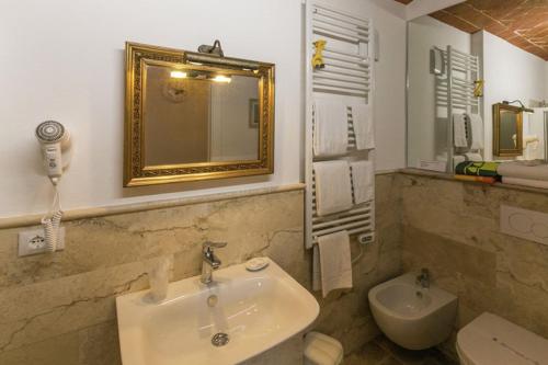 a bathroom with a sink and a mirror and a toilet at Agriturismo Casal Gheriglio in Lucignano