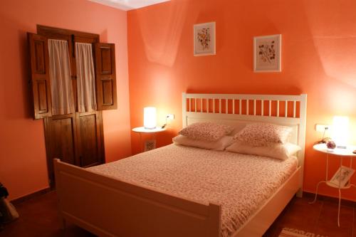 a bedroom with orange walls and a bed with pillows at La Posada del Recovero in Genalguacil