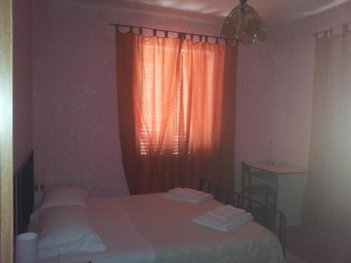 a bedroom with a bed and a window with an orange curtain at Vacanze Deaf in Rome