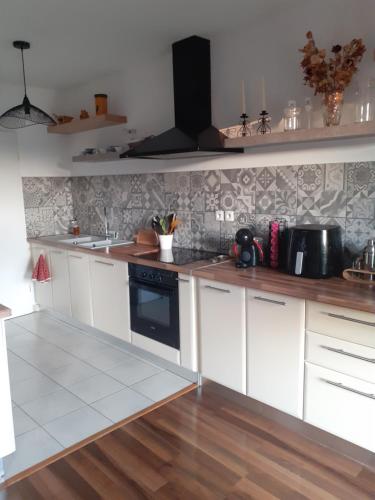 - une cuisine avec des placards blancs et une cuisinière noire dans l'établissement Bichette, à Cavaillon