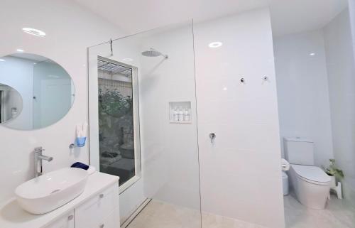 a white bathroom with a sink and a shower at Debbie's Place in Rainbow Beach