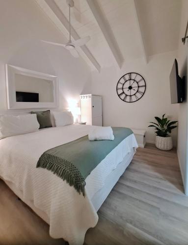 a white bedroom with a large bed and a clock at Debbie's Place in Rainbow Beach