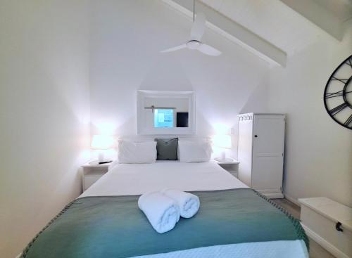 a white bedroom with a bed with towels on it at Debbie's Place in Rainbow Beach