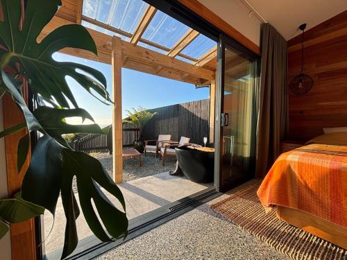 a bedroom with a large glass door leading to a patio at Pahautane Ridge - Elevated Sea Views Outdoor Stone Bath in Punakaiki