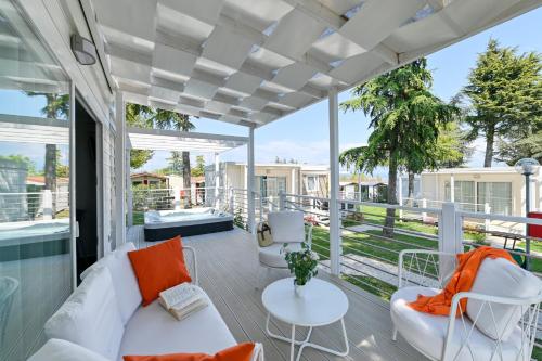 an outdoor living room with a white couch and orange pillows at San Benedetto Camping Relais in Peschiera del Garda
