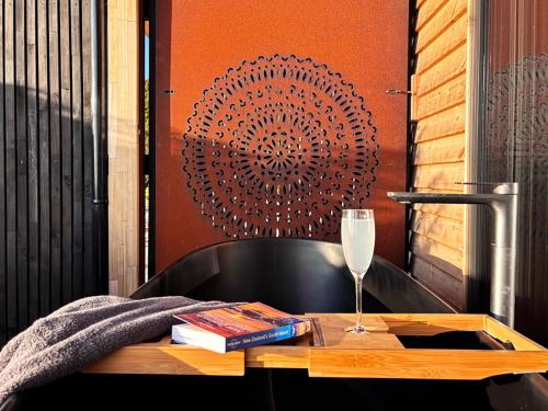 a table with a glass of wine and a book at Pahautane Ridge - Elevated Sea Views Outdoor Stone Bath in Punakaiki