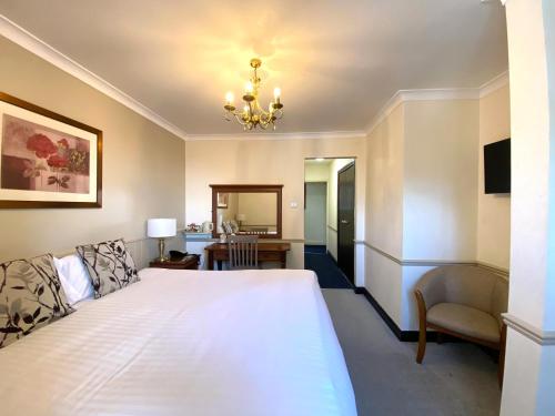 a bedroom with a large white bed and a chair at Best Western The Webbington Hotel & Spa in Loxton