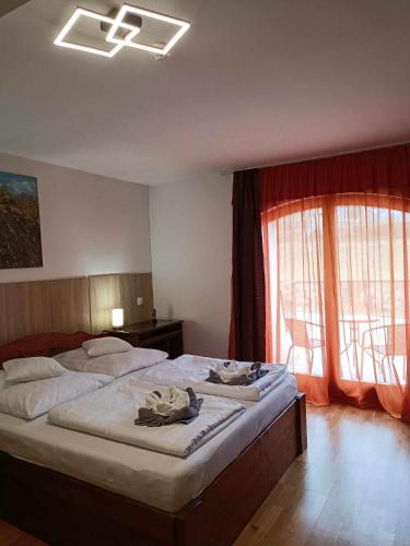 a bedroom with a large bed and two windows at Margaréta Apartman és Üdülőház in Bogács