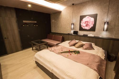 a bedroom with a large bed and a chair at ホテル アンジュエトワール 堺 - Adult Only in Sakai