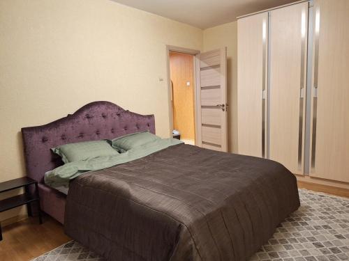 a bedroom with a large bed with a purple headboard at Emvika Tauragė apartment in Tauragė