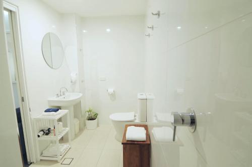a white bathroom with a toilet and a sink at Debbie's Place in Rainbow Beach