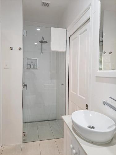 a white bathroom with a sink and a shower at Debbie's Place in Rainbow Beach