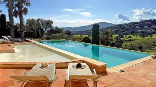 une piscine avec deux chaises et une table dans l'établissement Villa Les Amandiers, à Sainte-Maxime