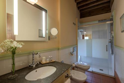 a bathroom with a sink and a toilet and a mirror at Hotel San Antonio el Real in Segovia
