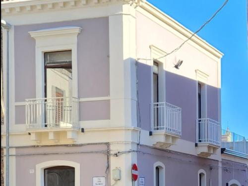 a white building with balconies on the side of it at Palazzo Grecale Dell'Etna in Aci SantʼAntonio