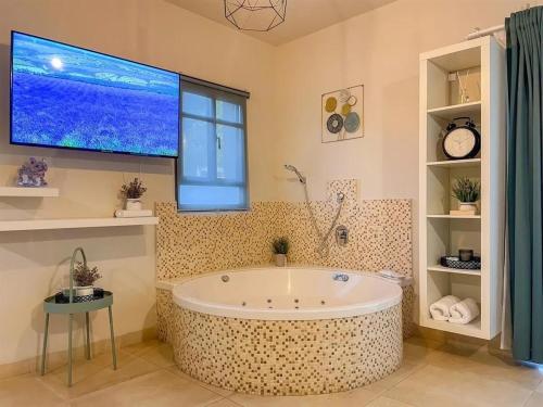 a large bathroom with a tub and a large tv at סוויטות טיפאני של רשת לב הגולן - 3 סוויטות מדהימות עם בריכה פרטית in Had Nes