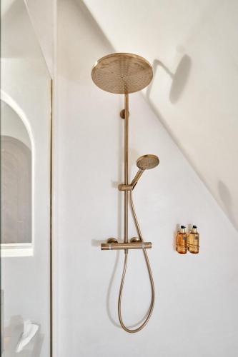 a shower in a bathroom with a brass light on the wall at Matca Hotel Relais & Châteaux in Şimon