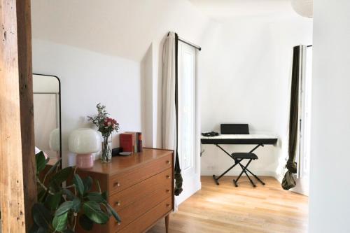 Cette chambre comprend une commode et un bureau avec un miroir. dans l'établissement Appartement Candie - Welkeys, à Paris