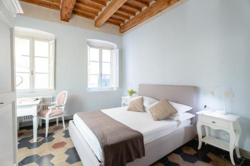 a white bedroom with a bed and a desk at San Martino Suite in Pisa