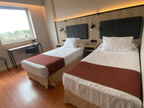 a hotel room with two beds and a window at Posadas de España Pinto in Pinto