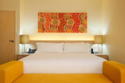 a bedroom with a white bed and a painting on the wall at Crowne Plaza Alice Springs Lasseters by IHG in Alice Springs
