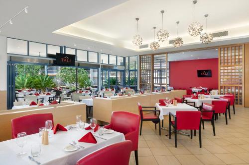 a restaurant with white tables and red chairs at Crowne Plaza Alice Springs Lasseters by IHG in Alice Springs